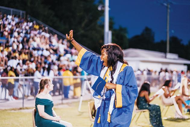 An overjoyed graduate waves to family and friends after receiving her diploma Friday night.