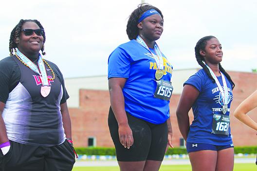 Palatka’s Torryence Poole (left) smiles after receiving her gold medal for winning the FHSAA 2A shot put championship for the second straight year on May 12 at the University of Florida. (MARK BLUMENTHAL / Palatka Daily News)