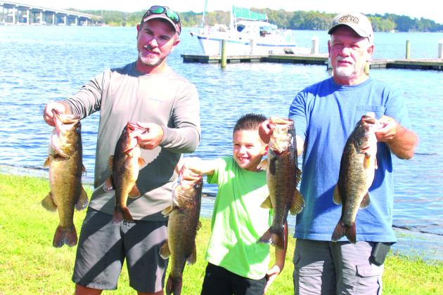 Justin Atkinson, Justin Atkinson, Jr. and Brett Bollinger hold up their winning fish at the Invitational Bass Tournament last weekend. (GREG WALKER / Daily News correspondent)