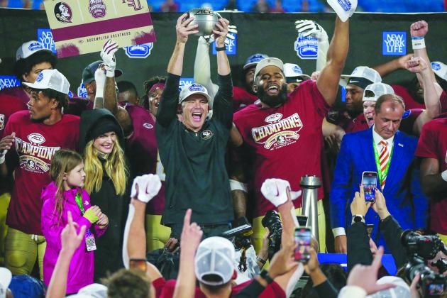 Florida State head football coach Mike Norvell holds the ACC championship aloft while celebrating with the Seminoles’ Fabien Lovett Sr. (right) after the team’s 16-6 victory over Louisville in Charlotte, North Carolina on Saturday night. (GREG OYSTER / Special to the Daily News)