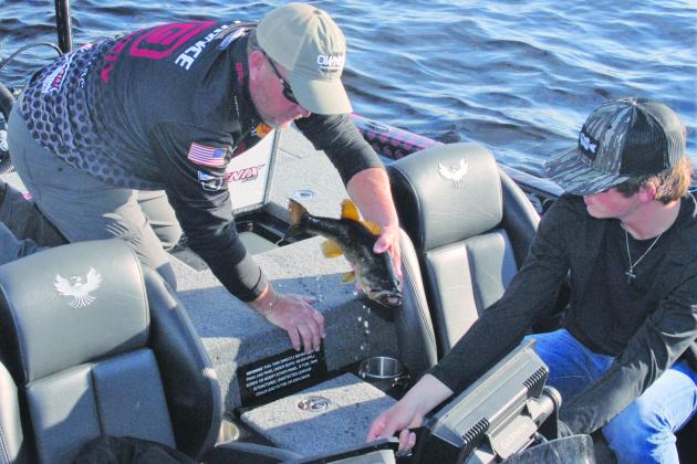 Palatka’s Cliff Prince (left) gets help from his son, Syler, in loading bass into a bag before weigh-ins on the opening day of the 2022 Bassmaster Elite at the St. Johns River tournament. (GREG WALKER / Daily News correspondent)