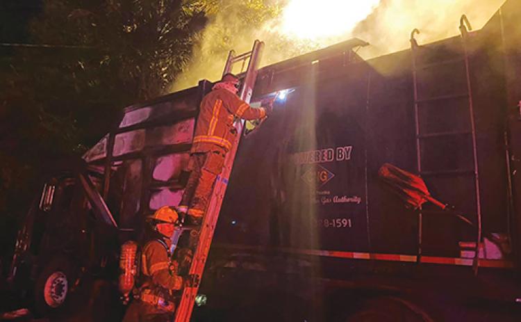 Firefighters rush to extinguish the flames inside a city of Palatka garbage truck at about 3 a.m. Tuesday.