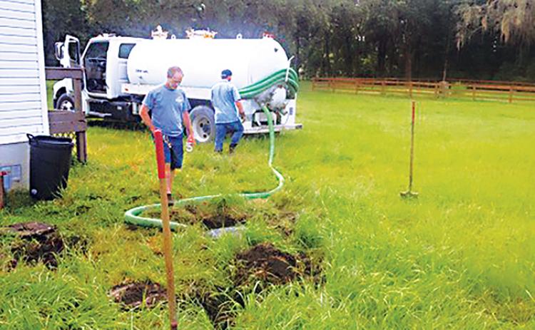 Lane’s Septic Tank Service employees drain a septic tank with a pump.