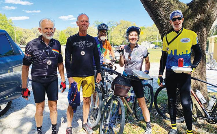 Cycling enthusiasts smile with their medals and trays full of barbecue on Saturday after completing a Celebrate Trails ride in Florahome. 