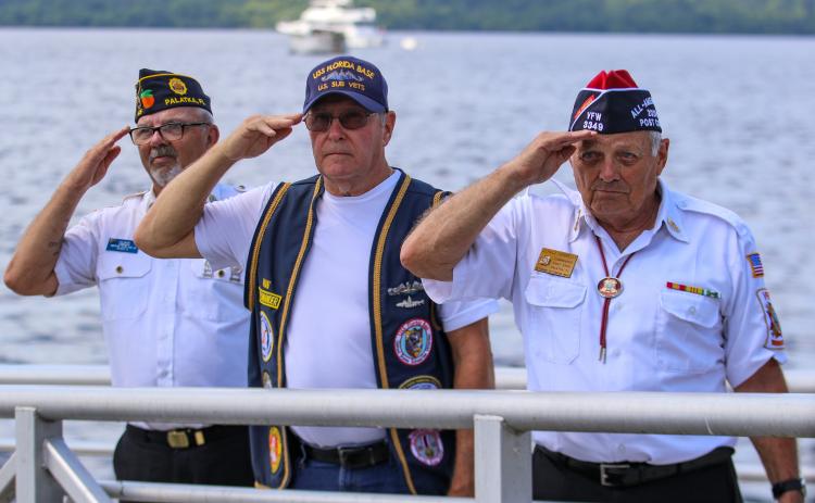 (From left to right) American Legion Bert Hodge Post 45 Commander Ken Moore, U.S. Submarine Veterans Inc. Base Commander Ron Swiggert and Gerald Donnelly, commander of Veterans of Foreign Wars Post 3349 in Palatka salute poppies in the water that represent fallen soldiers as taps play along the Palatka riverfront.  