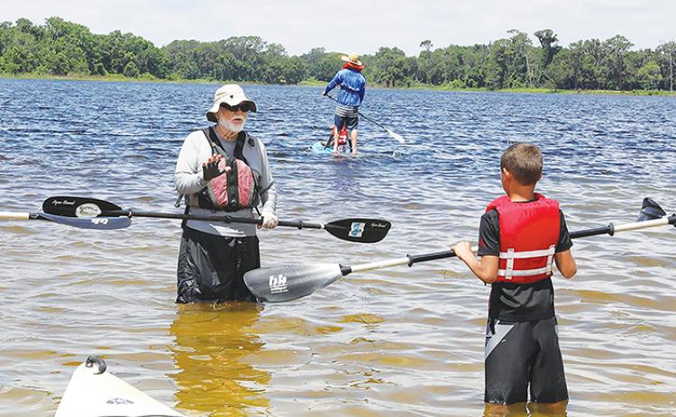 A volunteer instructs a child about how to paddleboard during last year’s Cops, Kids and Kayaks.