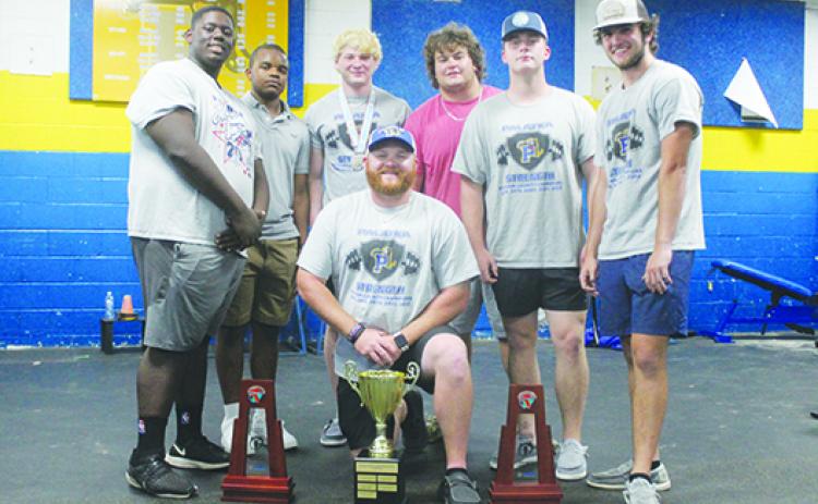 Palatka’s Dustin Whitlock (center, kneeling), who recently stepped down as the Panthers’ boys weightlifting coach, is surrounded by the trophies his team won this spring along with team members Daunte Wilkerson, Dalvin Dallas, Adaris Medina, Carson Tibbs, Luke Wilhite and Jason Purcell. (MARK BLUMENTHAL / Palatka Daily News)