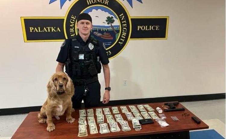 Officer Blaine Snyder and the Palatka Police Department's drug dog, Tito, stand with a table full of seized evidence after Tuesday's arrest.