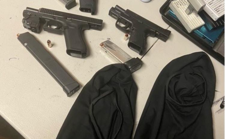 Three semi-automatic rifles and two black ski masks sit on a table after police reportedly seized them from Jacksonville residents who were visiting Palatka.