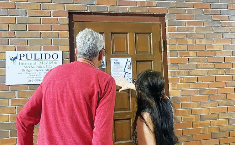 Michael Mallin and Lucille Harvey, both former patients of Dr. Alex Pulido, read a sign on the late doctor’s door Wednesday informing people how to get ahold of their medical records.