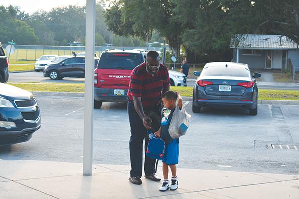 File photo – Justin Campbell, who oversees the Putnam County School District’s Reach One Teach One Mentoring Program, helps a child at Moseley Elementary School in Palatka on the first day of the 2023-2024 academic year.